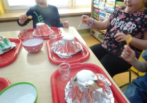 Dwójka dzieci z zaskoczeniem ogląda efekt erupcji wulkanu.
